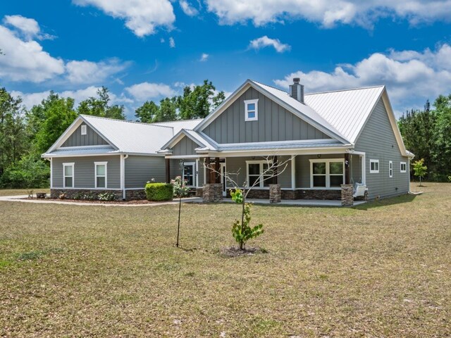 craftsman-style home featuring board and batten siding, a porch, a front yard, and stone siding