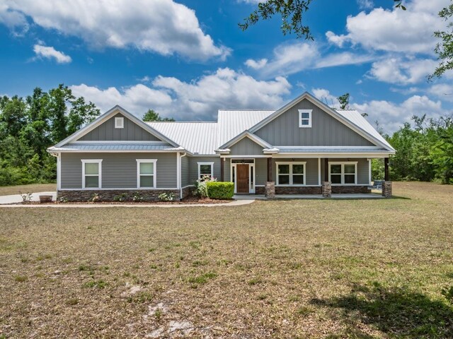 craftsman-style house featuring board and batten siding, a front yard, covered porch, and stone siding