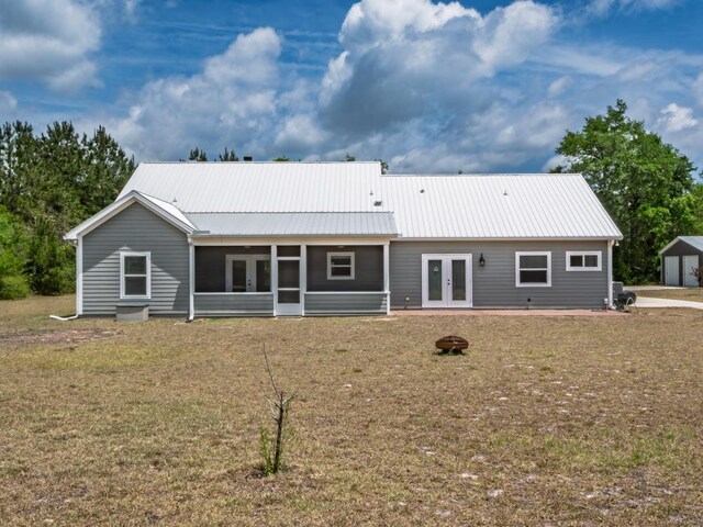 rear view of property featuring a lawn, french doors, metal roof, and a sunroom