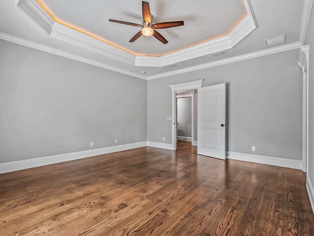 interior space with ornamental molding, a raised ceiling, ceiling fan, and wood finished floors