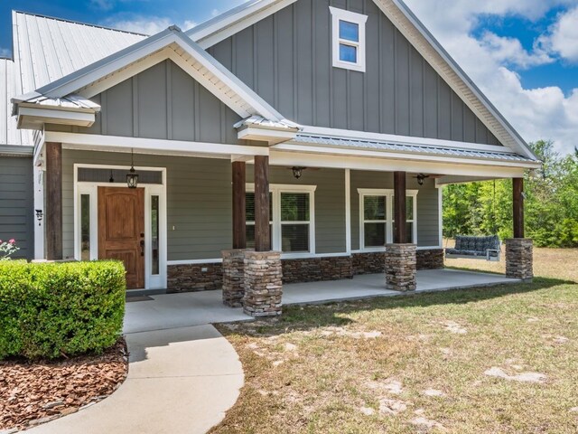 craftsman house featuring board and batten siding, metal roof, covered porch, and stone siding