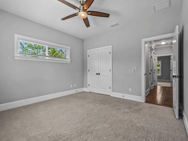 unfurnished bedroom featuring multiple windows, carpet flooring, attic access, and visible vents