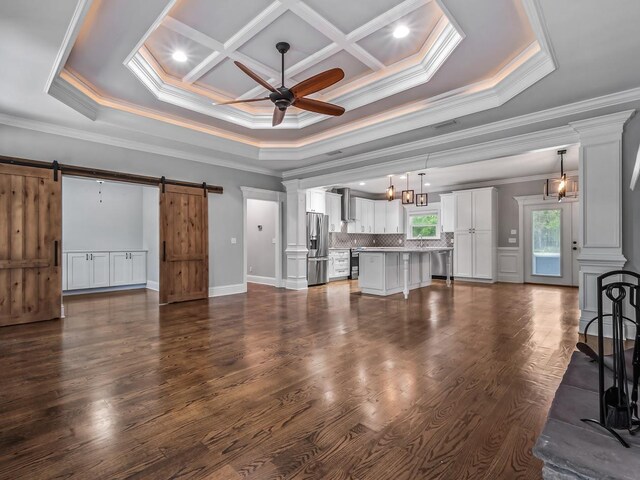 unfurnished living room featuring crown molding, baseboards, ceiling fan, dark wood-style floors, and a barn door