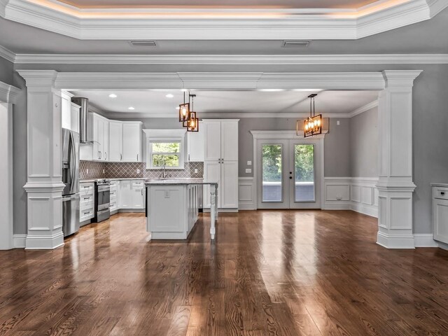 kitchen with decorative columns, dark wood-style flooring, white cabinetry, and stainless steel appliances