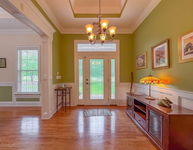 entryway with light wood-style flooring, wainscoting, and a notable chandelier