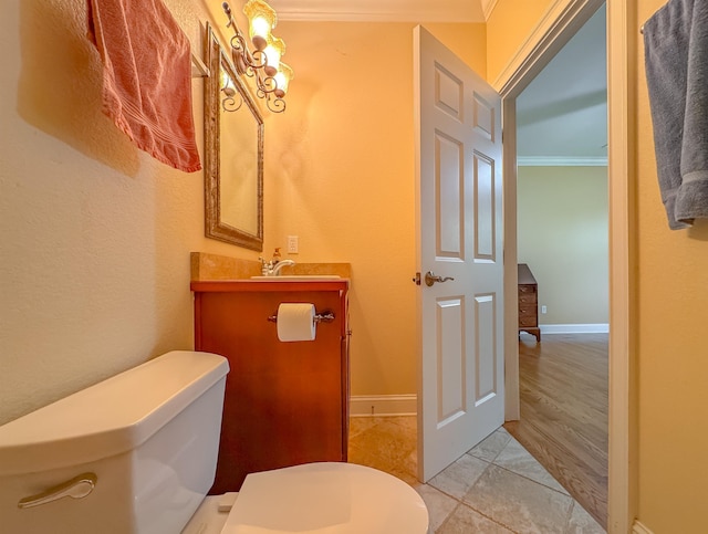 half bathroom with vanity, ornamental molding, baseboards, and toilet