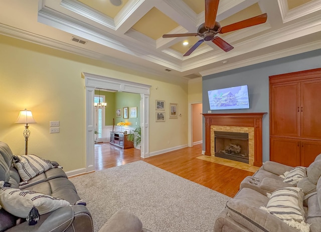 living room featuring visible vents, crown molding, ceiling fan with notable chandelier, light wood-style floors, and coffered ceiling