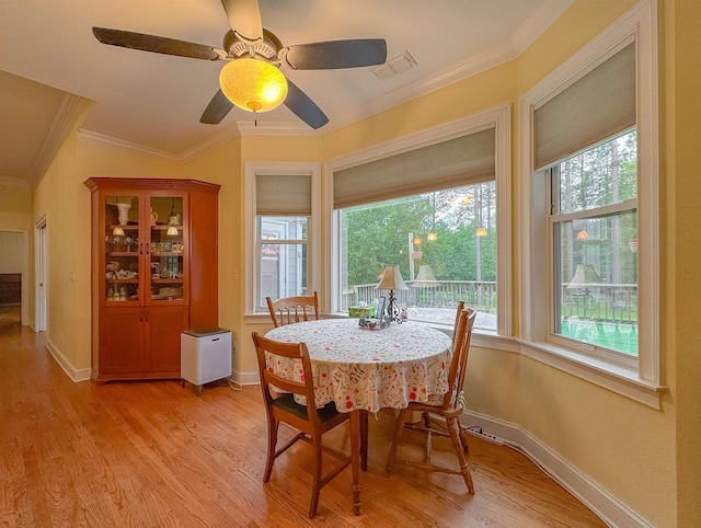 dining room with visible vents, ornamental molding, baseboards, ceiling fan, and light wood-style flooring