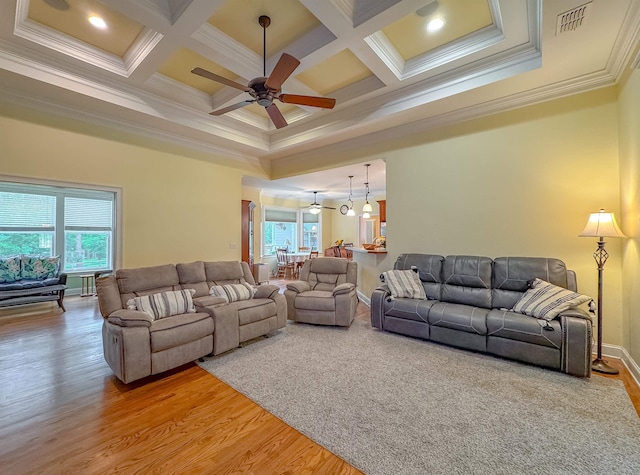 living area featuring ceiling fan, ornamental molding, light wood finished floors, and coffered ceiling