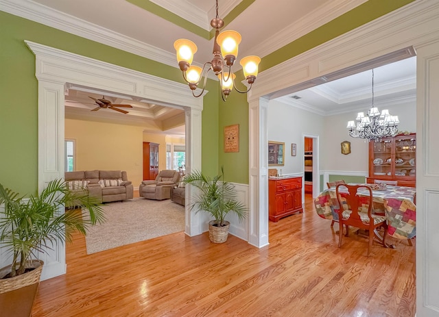 dining area with crown molding, wainscoting, light wood finished floors, and ceiling fan with notable chandelier