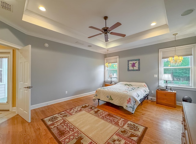 bedroom with light wood-type flooring, ornamental molding, and a tray ceiling