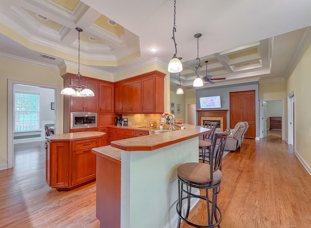 kitchen with ceiling fan with notable chandelier, stainless steel microwave, coffered ceiling, and a glass covered fireplace
