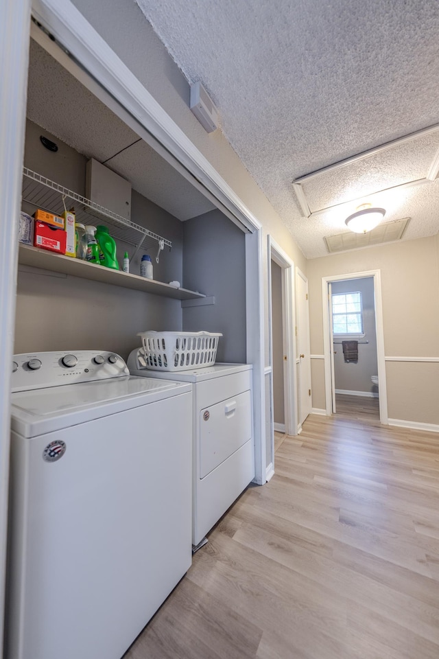 laundry area with independent washer and dryer, a textured ceiling, and light hardwood / wood-style flooring