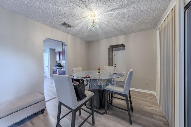 dining space with light hardwood / wood-style floors and a textured ceiling