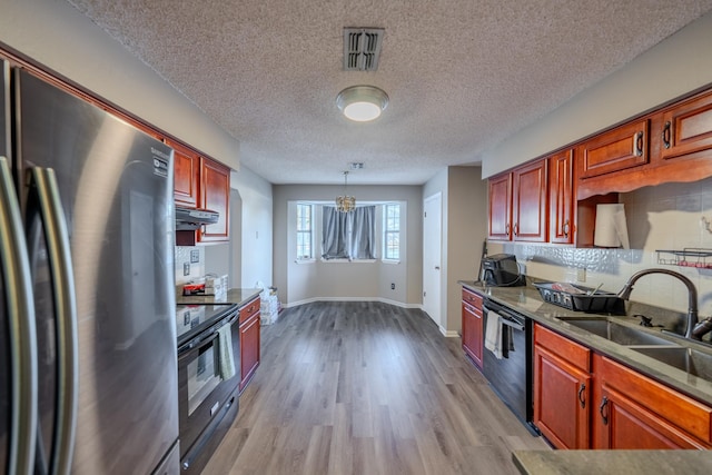 kitchen with a notable chandelier, a textured ceiling, pendant lighting, light hardwood / wood-style flooring, and black appliances