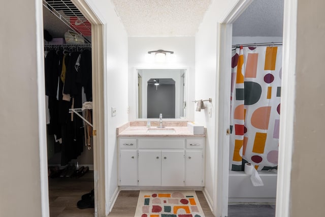 bathroom featuring vanity, shower / bath combination with curtain, a textured ceiling, and hardwood / wood-style flooring