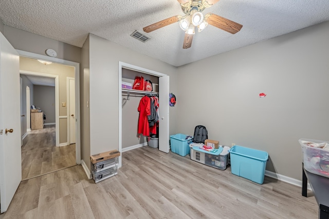 bedroom featuring a textured ceiling, ceiling fan, a closet, and light hardwood / wood-style flooring