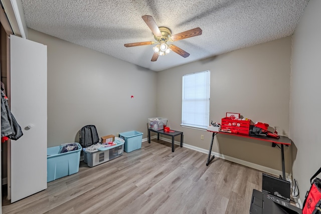 recreation room featuring ceiling fan, a textured ceiling, and light hardwood / wood-style flooring