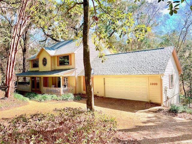 view of front of property featuring a garage, dirt driveway, and a porch