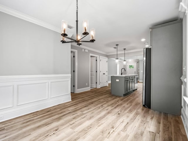 kitchen featuring stainless steel fridge, an island with sink, a chandelier, decorative light fixtures, and gray cabinets