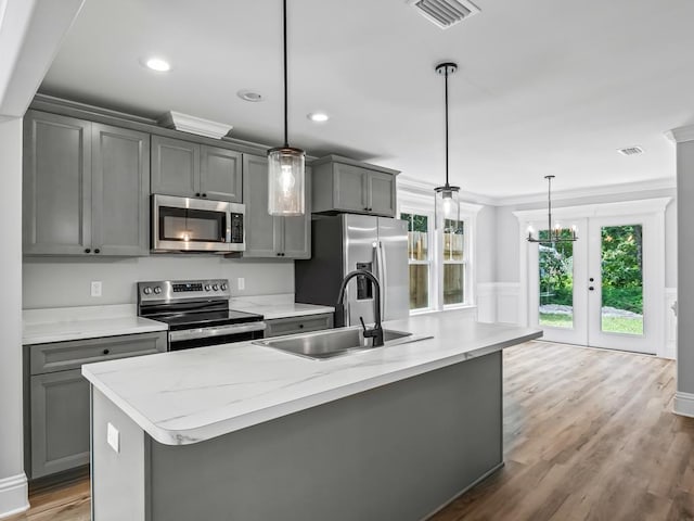 kitchen with pendant lighting, gray cabinetry, sink, an island with sink, and appliances with stainless steel finishes