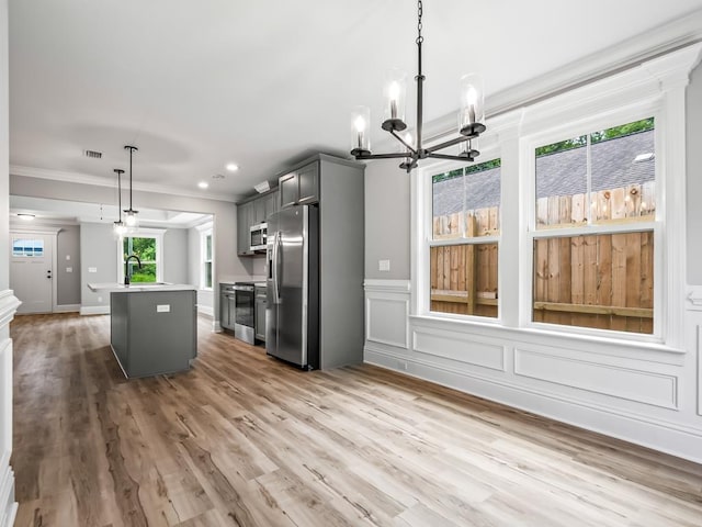 kitchen with appliances with stainless steel finishes, gray cabinetry, sink, decorative light fixtures, and a center island