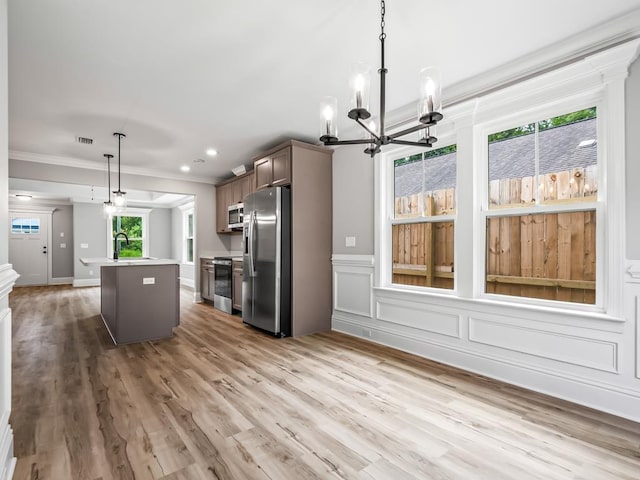 kitchen featuring a center island, sink, hanging light fixtures, appliances with stainless steel finishes, and a healthy amount of sunlight