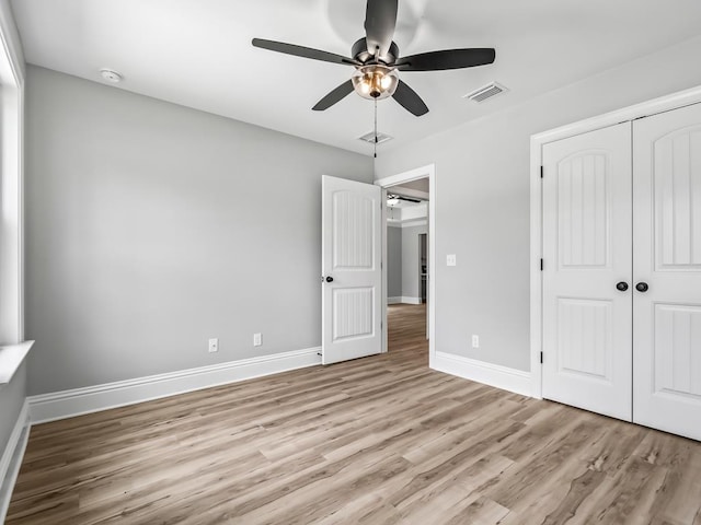 unfurnished bedroom featuring a closet, light hardwood / wood-style flooring, and ceiling fan