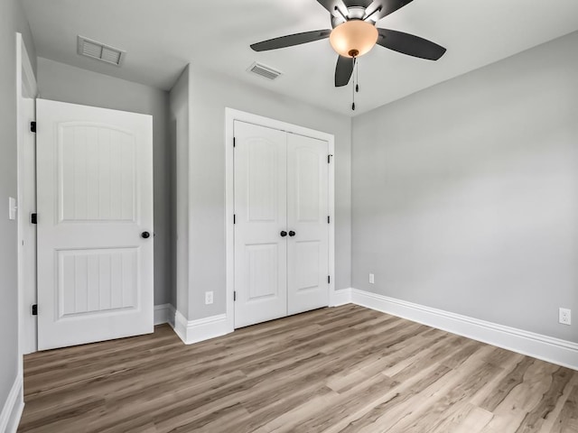 unfurnished bedroom featuring ceiling fan, light wood-type flooring, and a closet