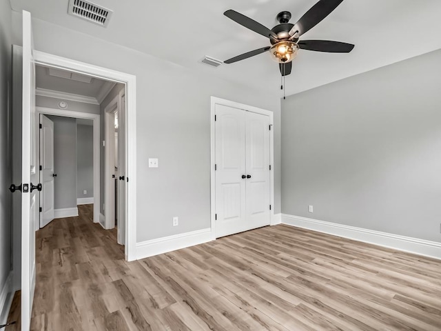 unfurnished bedroom featuring ceiling fan, a closet, light wood-type flooring, and ornamental molding