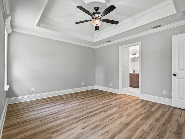 unfurnished bedroom with connected bathroom, a raised ceiling, ceiling fan, and ornamental molding