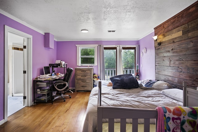 bedroom featuring a textured ceiling, visible vents, ornamental molding, access to outside, and hardwood / wood-style floors
