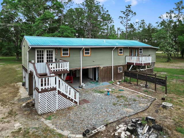 back of house featuring stairs, a wooden deck, and metal roof