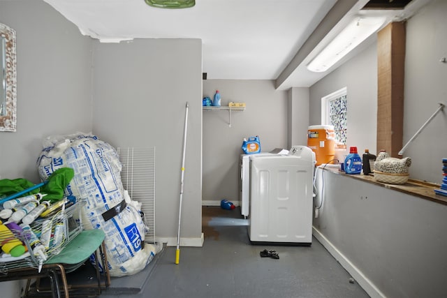 clothes washing area with baseboards, washing machine and dryer, and laundry area