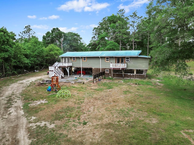 back of property with stairs, dirt driveway, a deck, and metal roof