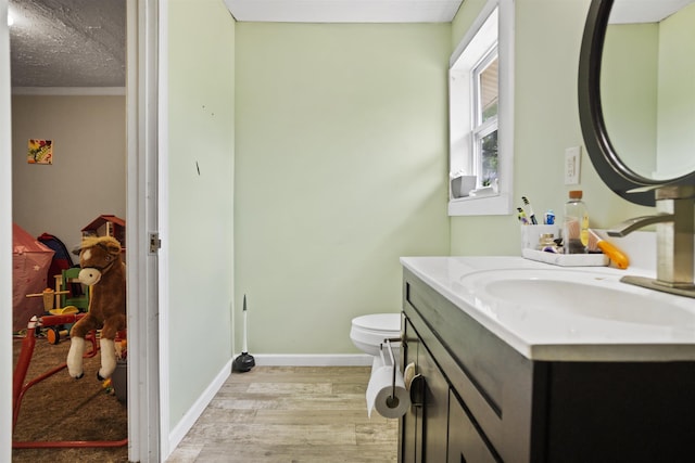 half bath featuring toilet, baseboards, wood finished floors, and vanity