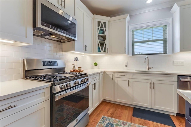 3837 Broadmore Ln, Tallahassee, FL 32308 - kitchen with appliances with stainless steel finishes, a sink, white cabinetry, light countertops, and crown molding