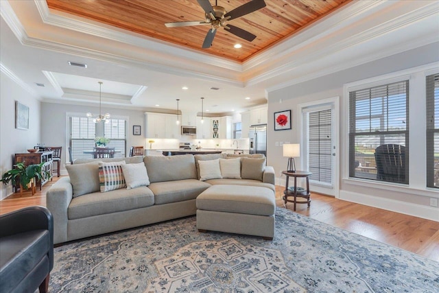 3837 Broadmore Ln, Tallahassee, FL 32308 - living area with a raised ceiling, a chandelier, a ceiling fan, light wood-style floors, and ornamental molding