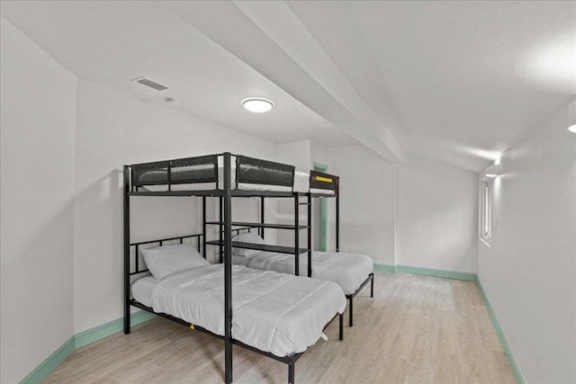 bedroom with vaulted ceiling and light wood-type flooring