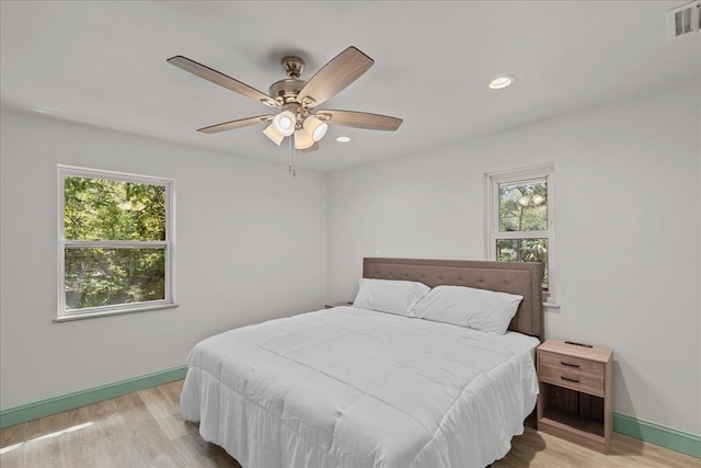 bedroom with multiple windows, ceiling fan, and light wood-type flooring