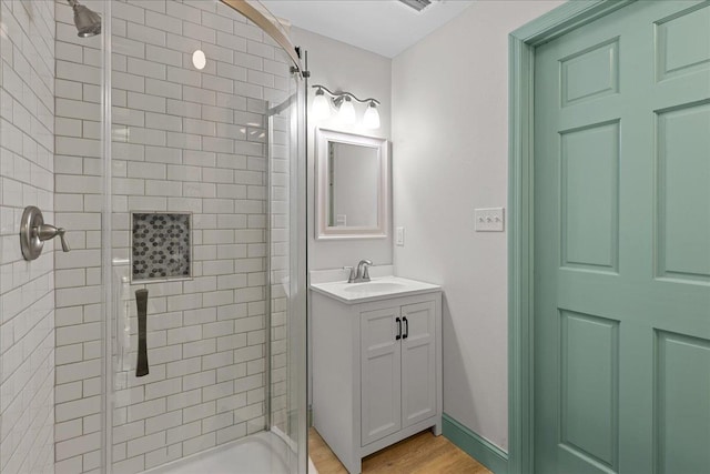 bathroom with vanity, wood-type flooring, and tiled shower