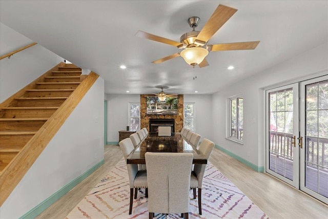 dining area featuring a fireplace, light hardwood / wood-style floors, french doors, and ceiling fan