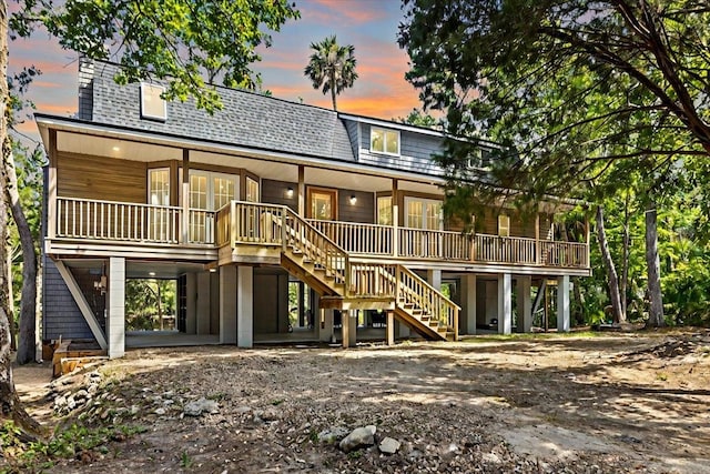 back house at dusk featuring a wooden deck