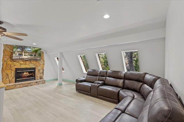 living room featuring a stone fireplace, ceiling fan, and light hardwood / wood-style flooring