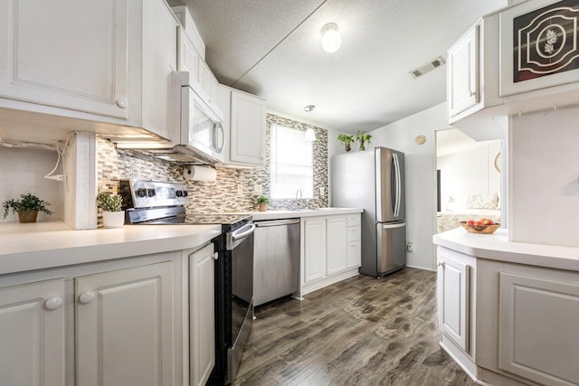 kitchen with appliances with stainless steel finishes, white cabinetry, light countertops, dark wood-style floors, and a textured ceiling