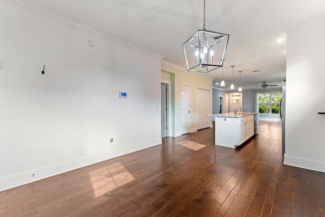kitchen featuring dark wood finished floors, baseboards, open floor plan, ornamental molding, and an island with sink