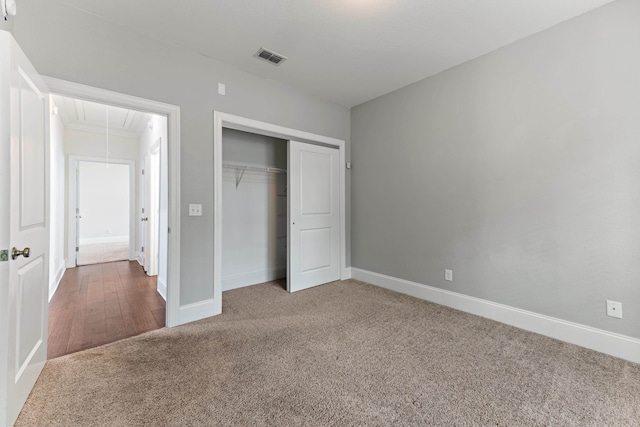 unfurnished bedroom featuring baseboards, carpet, attic access, and a closet