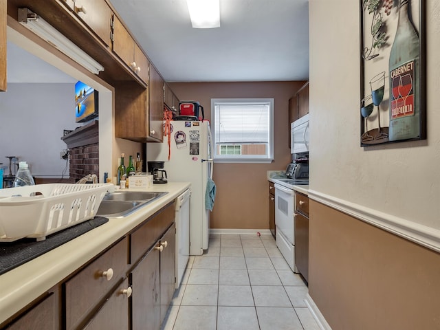 kitchen featuring light tile patterned floors, white appliances, and sink