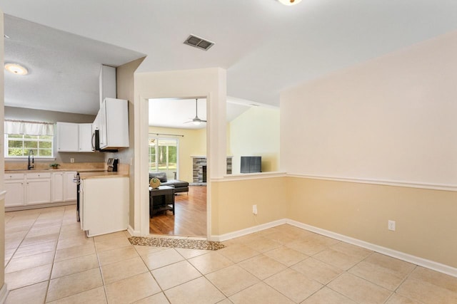 8325 Yellow Ln, Tallahassee, FL 32311 - kitchen with a ceiling fan, plenty of natural light, white cabinets, and light tile patterned flooring