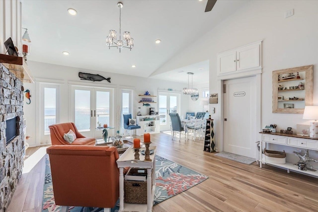 living room with french doors, a stone fireplace, plenty of natural light, vaulted ceiling, and a water view